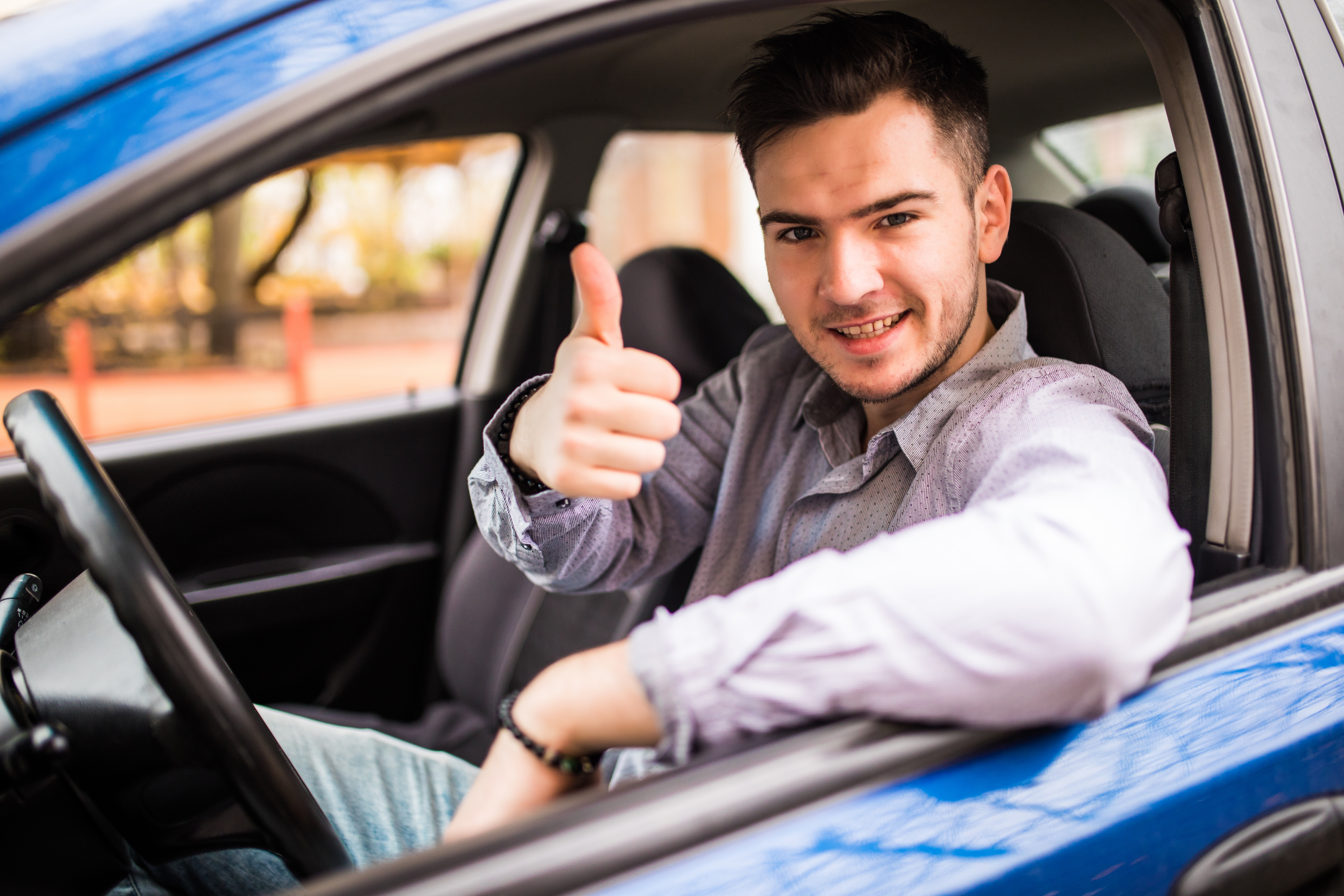 happy smiling man sitting inside car showing thumbs up handsome guy excited about his new vehicle positive face expression